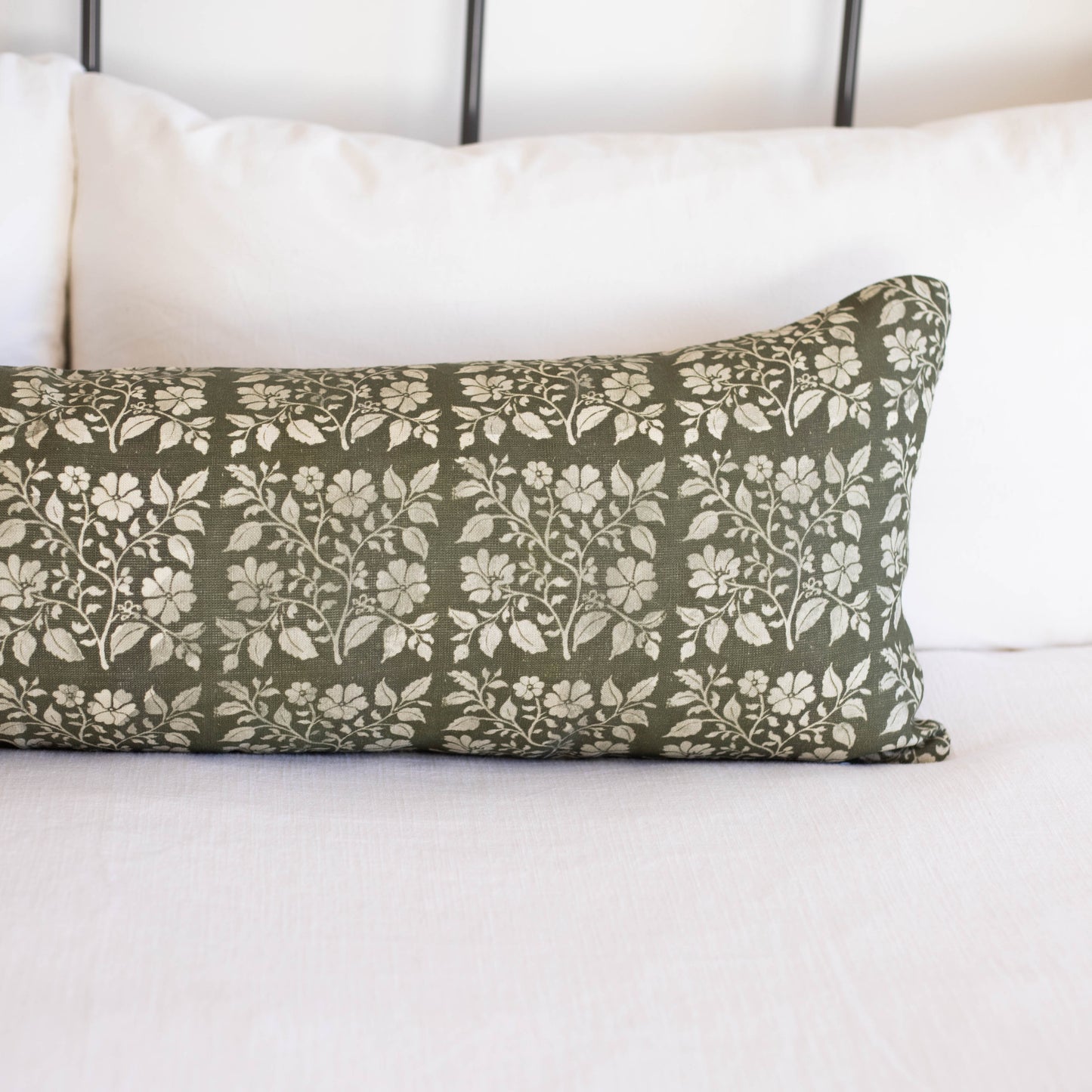 Rectangular lumbar pillow with sage green linen fabric featuring white floral and leaf pattern throughout.