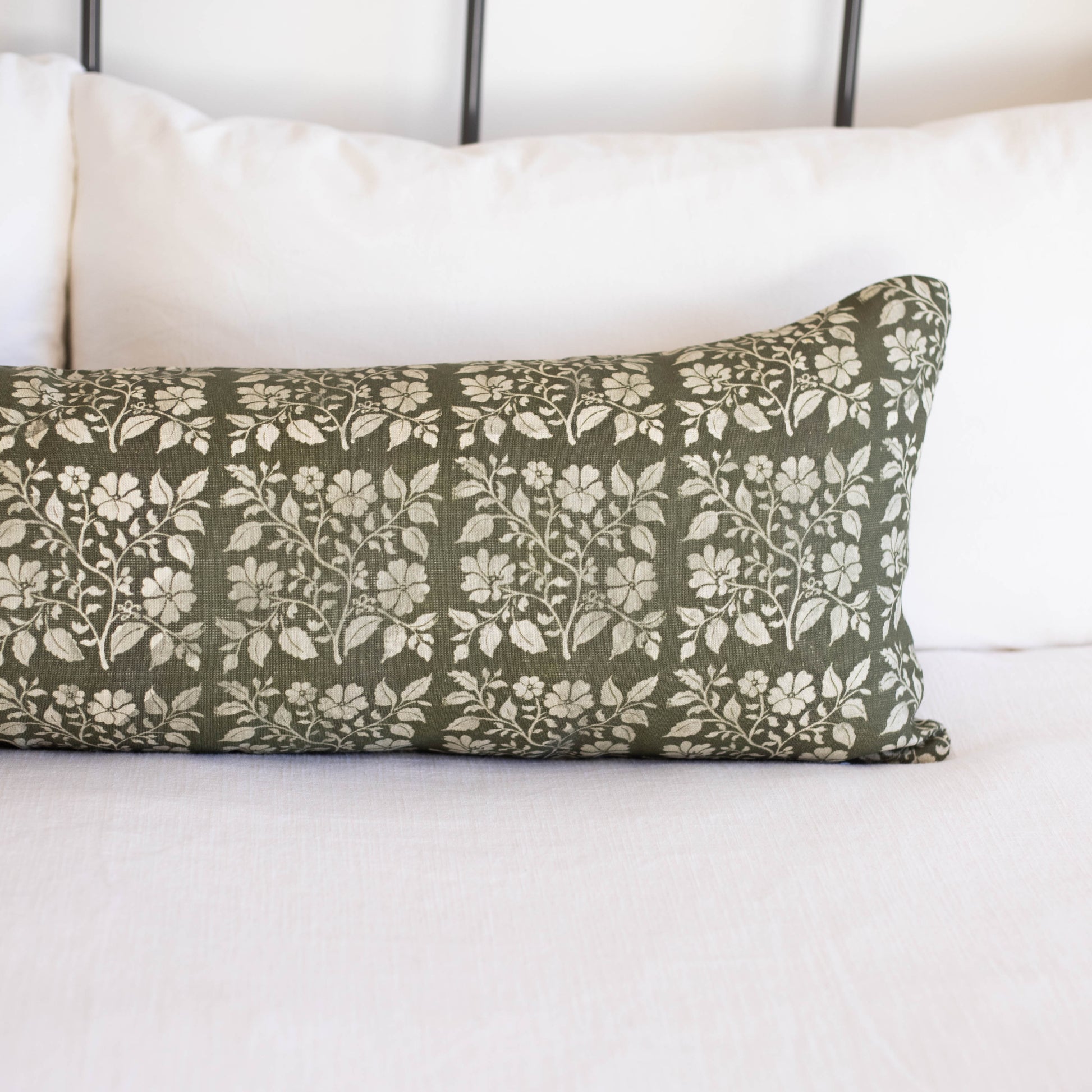 Rectangular lumbar pillow with sage green linen fabric featuring white floral and leaf pattern throughout.