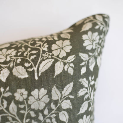 Rectangular lumbar pillow with cream floral pattern on sage green linen fabric.