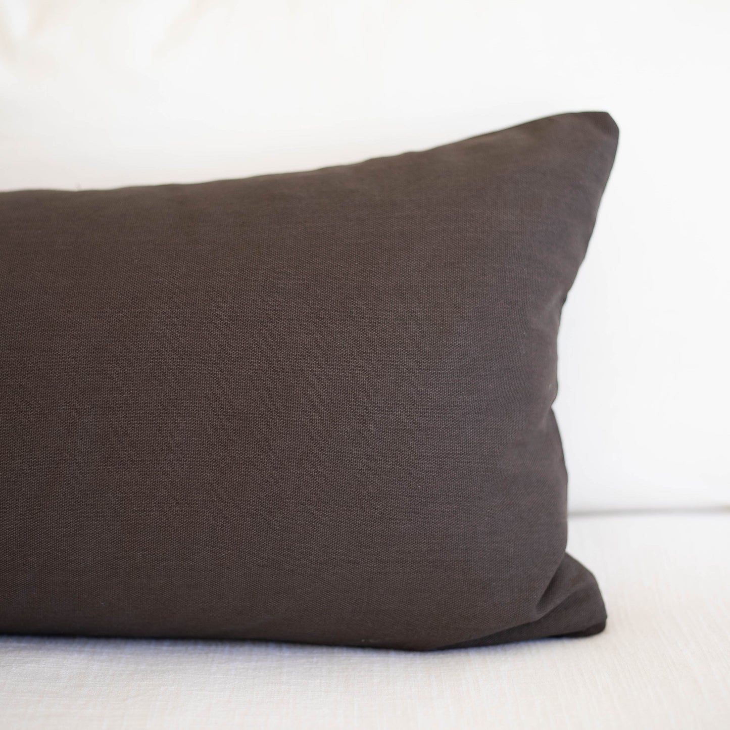 Dark gray lumbar pillow with solid woven fabric displayed on white background.