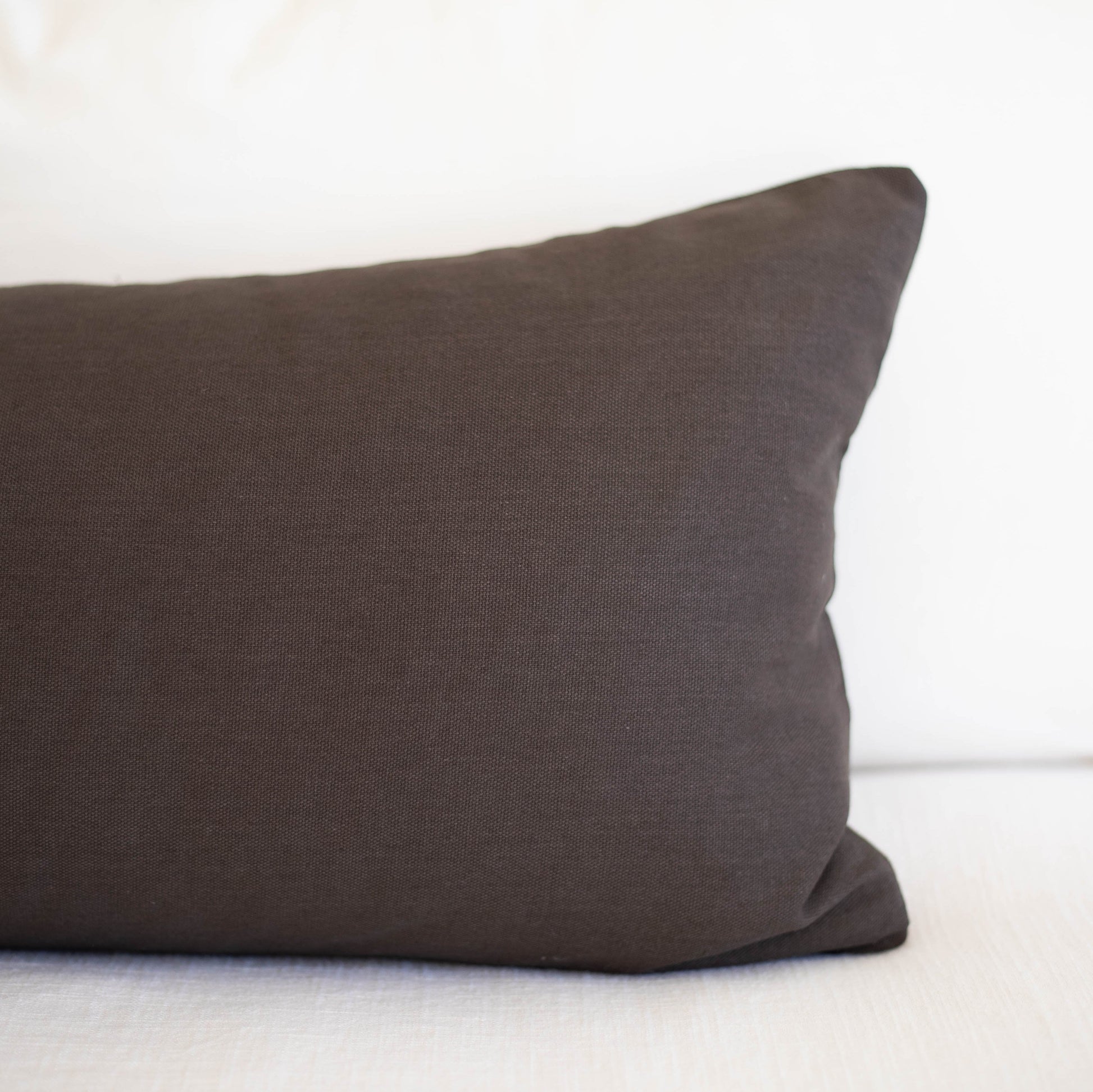 Dark gray lumbar pillow with solid woven fabric displayed on white background.