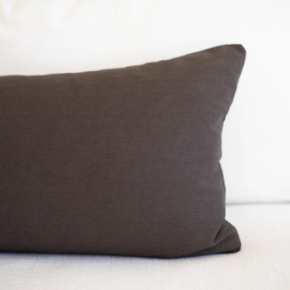 Dark gray lumbar pillow with solid woven fabric displayed on white background.