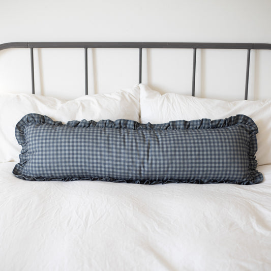 Navy gingham check lumbar pillow with ruffled edges on white bedding.