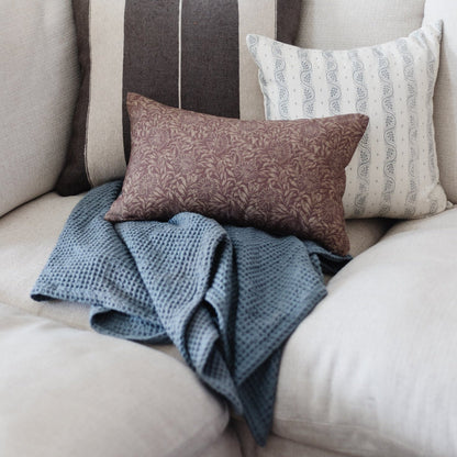 Storm blue waffle-textured blanket draped over a light-colored couch with decorative pillows.