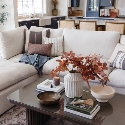 Beige lumbar pillow displayed on cream sectional sofa with coordinating cushions in living room setting.