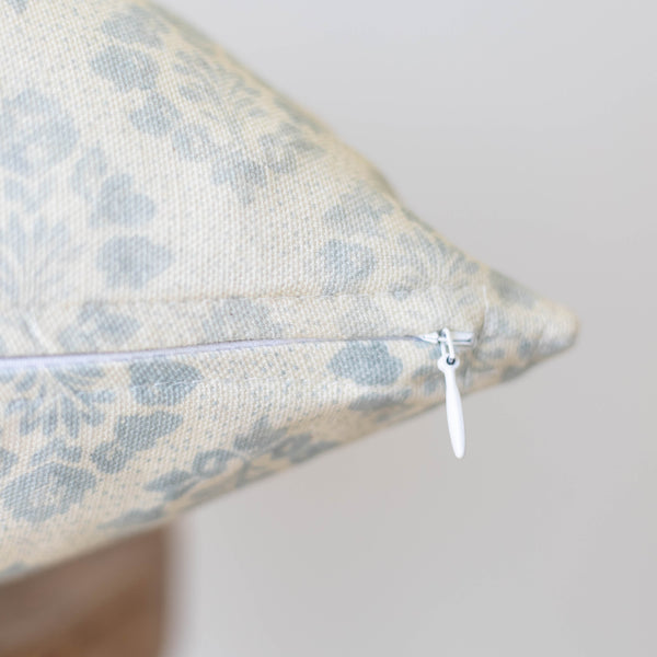 Cream and blue leopard print pillow with white zipper closure detail visible on seam.