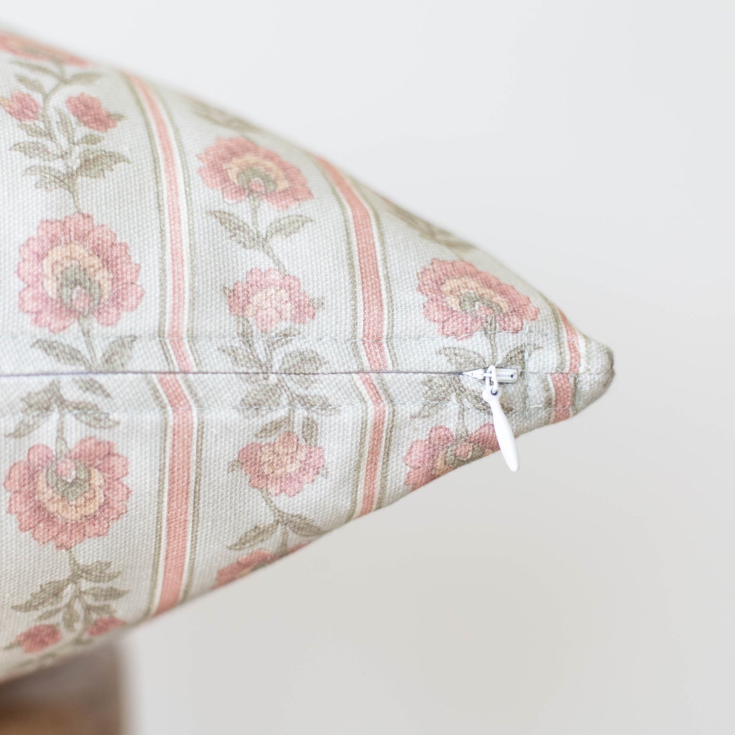 Cream linen pillow with pink floral pattern, vertical stripes, and white zipper closure.