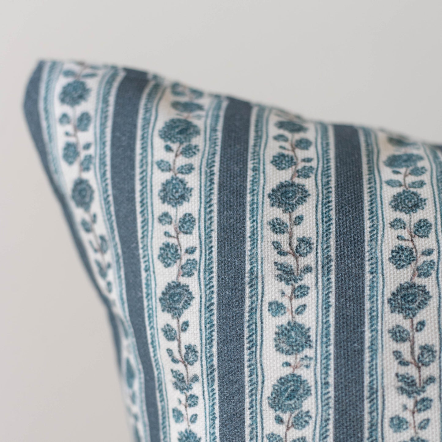 Teal and cream striped pillow with floral botanical motif pattern.