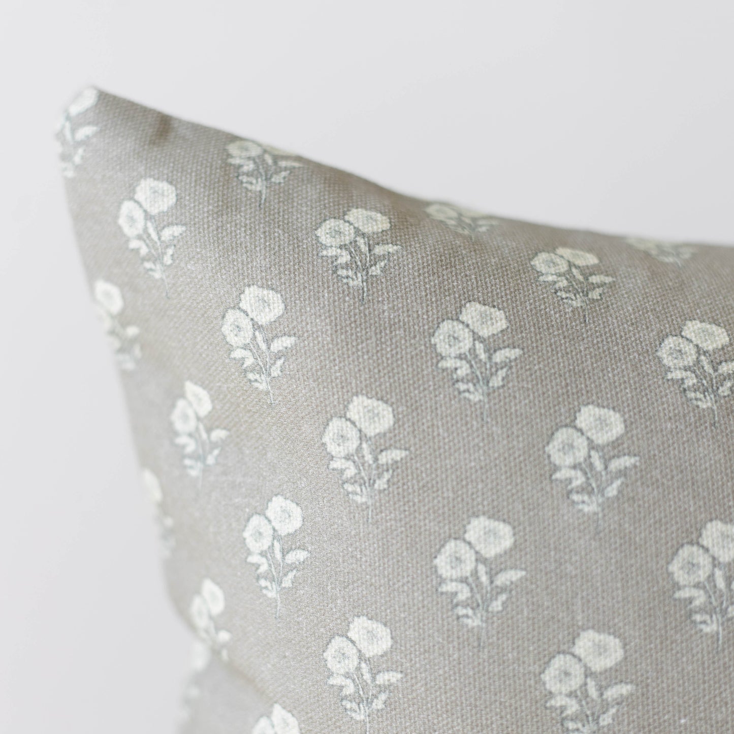 Beige linen pillow with repeating white floral botanical pattern throughout.