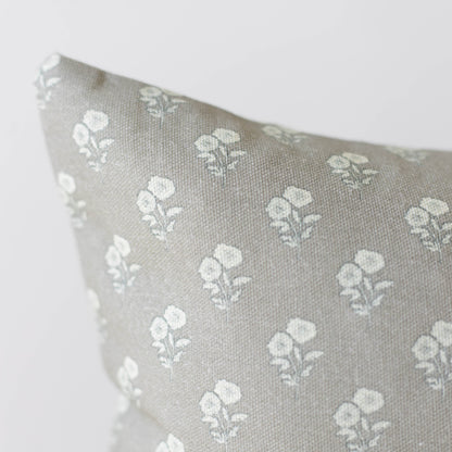 Beige linen pillow with repeating white floral botanical pattern throughout.