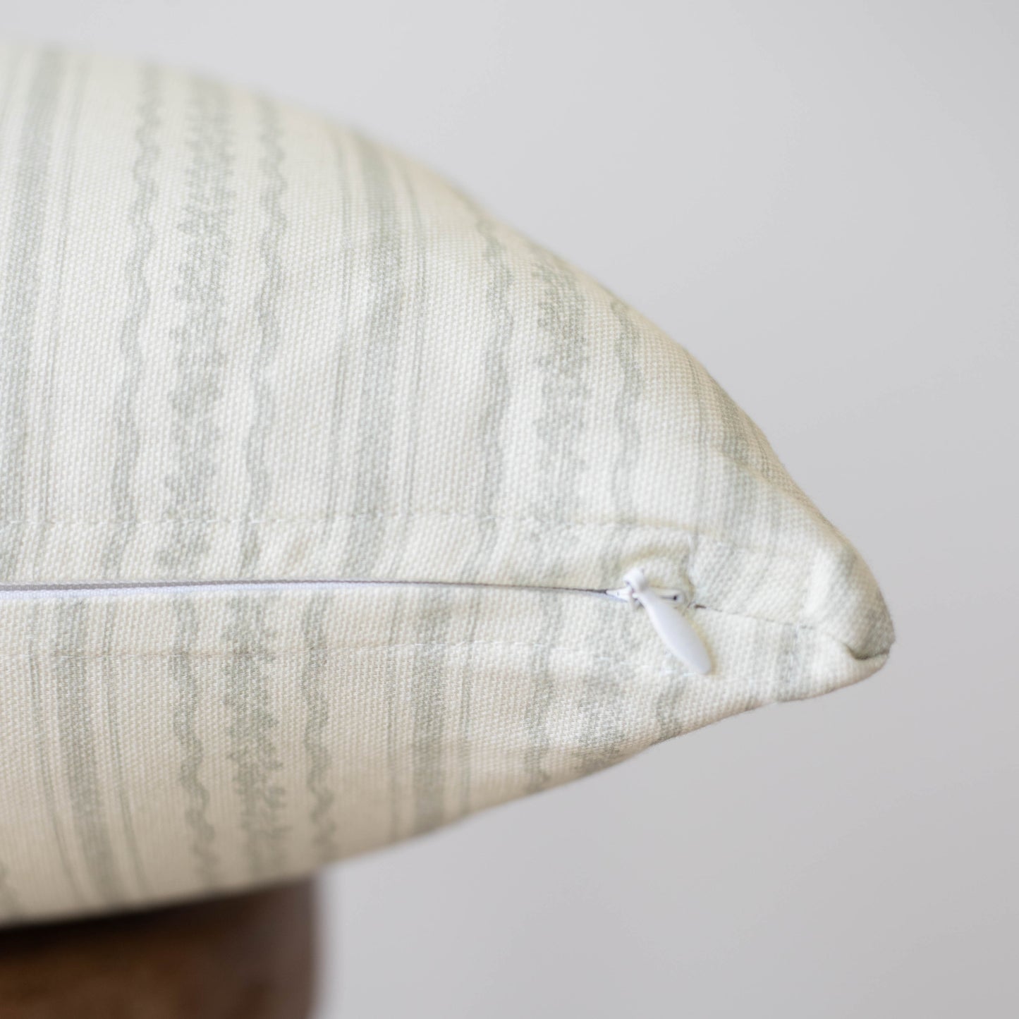 Cream textured pillow with geometric pattern and white zipper closure.