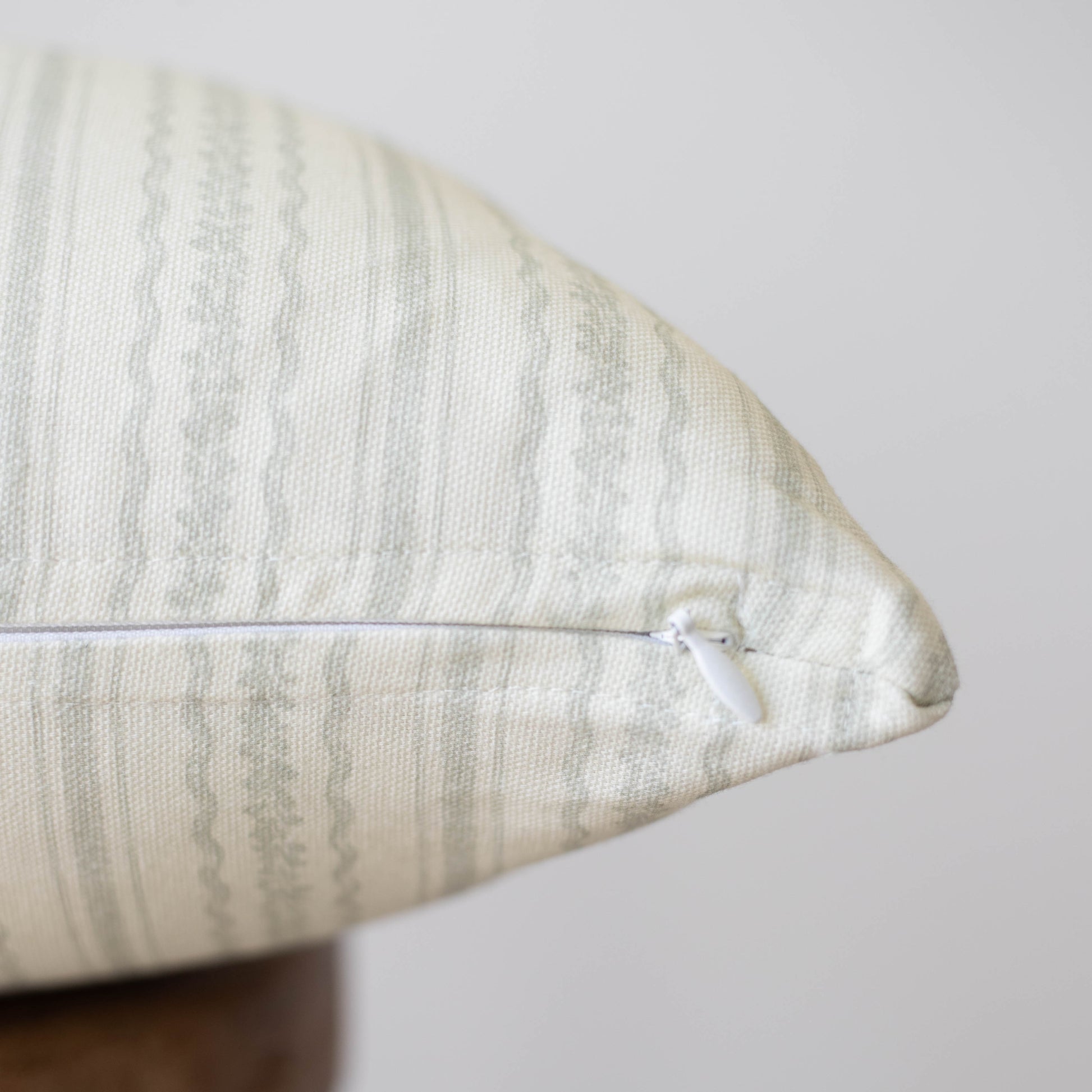 Cream textured pillow with geometric pattern and white zipper closure.
