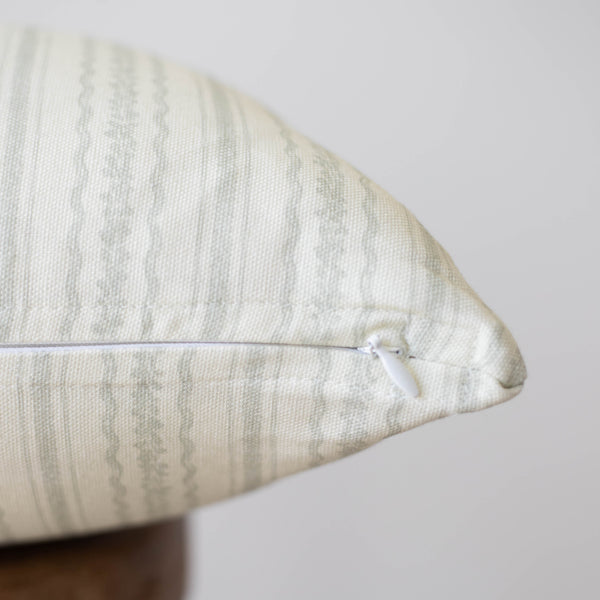 Cream textured pillow with geometric pattern and white zipper closure.