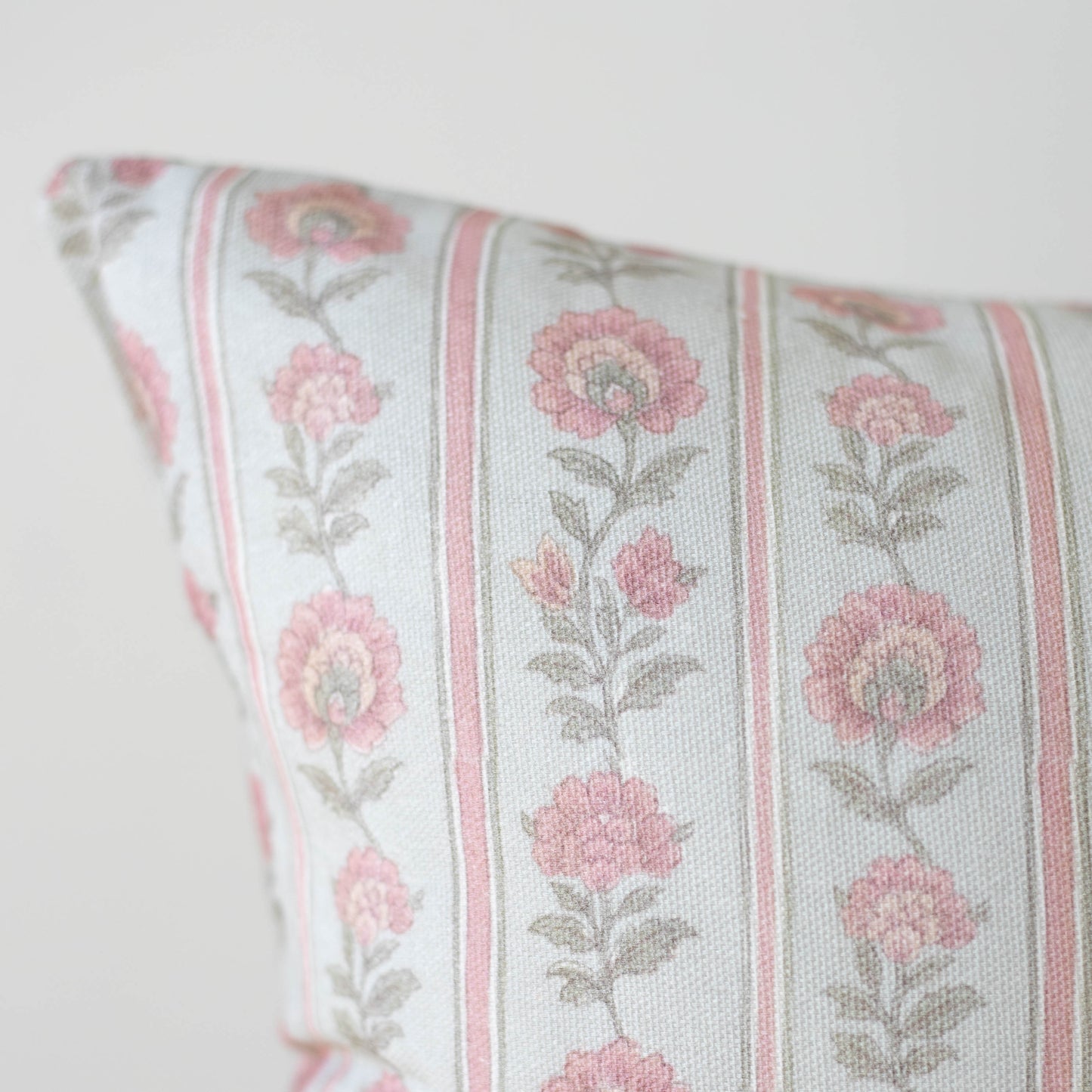 Decorative pillow with pink floral pattern and vertical stripes on cream background.