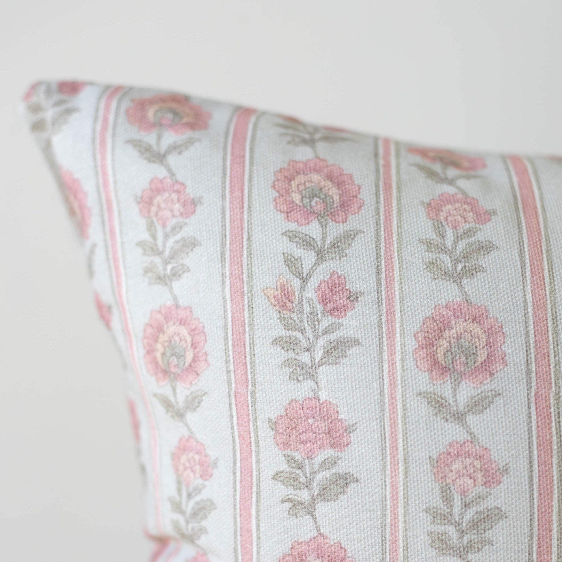 Decorative pillow with pink floral pattern and vertical stripes on cream background.