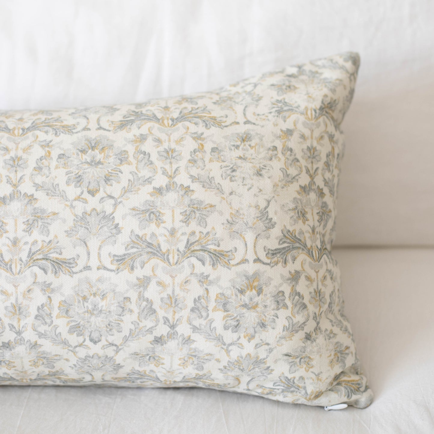 Rectangular pillow with cream and gray damask floral pattern fabric.