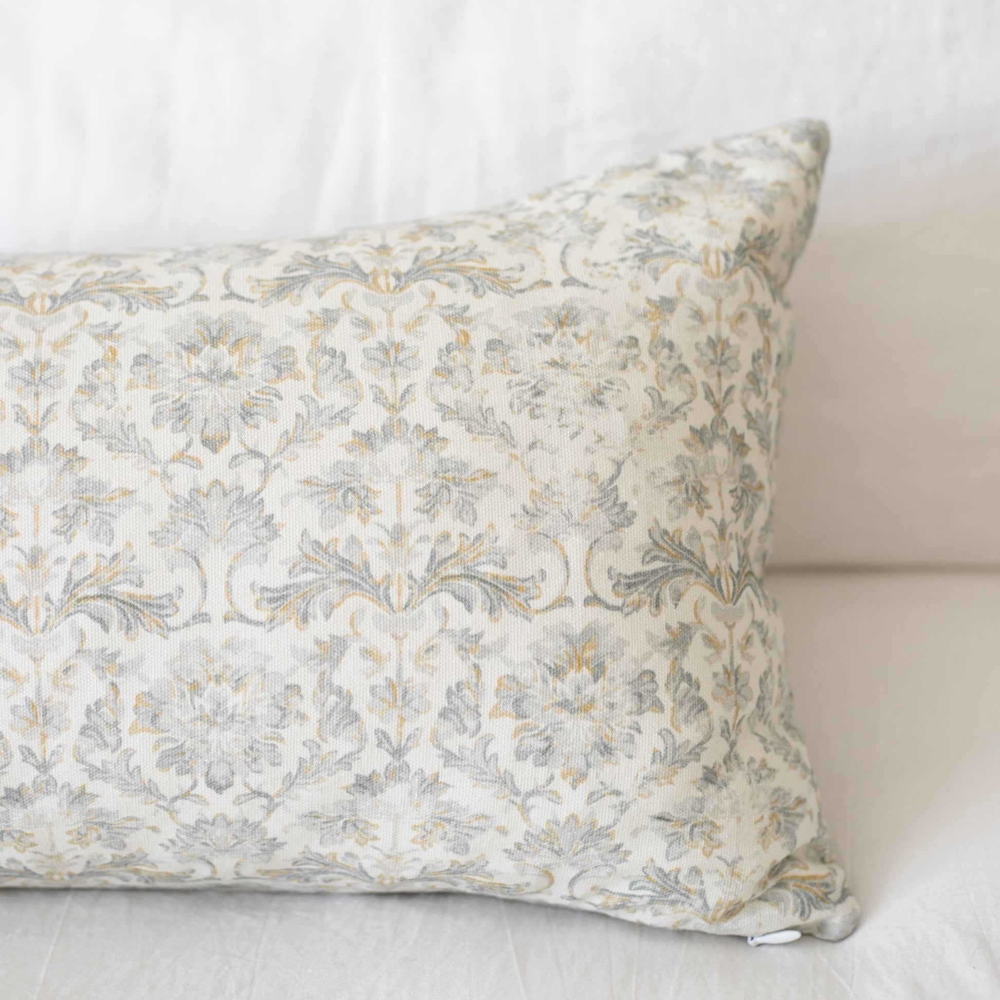 Rectangular pillow with cream and gray damask floral pattern fabric.