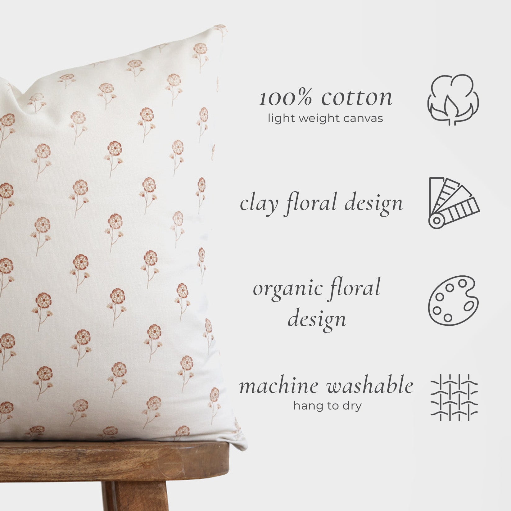 Cream cotton pillow with repeating tan floral stem pattern, displayed on wooden stool.