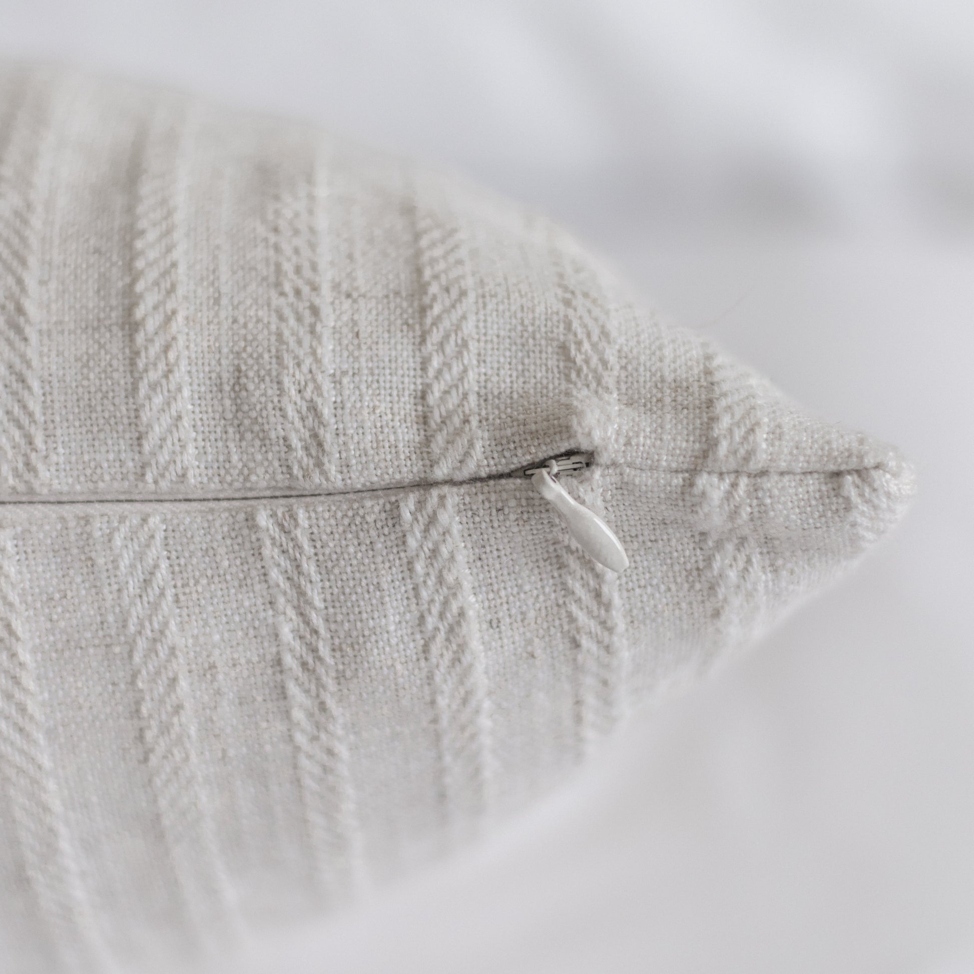Cream-colored pillow with textured cable knit pattern and side zipper closure.
