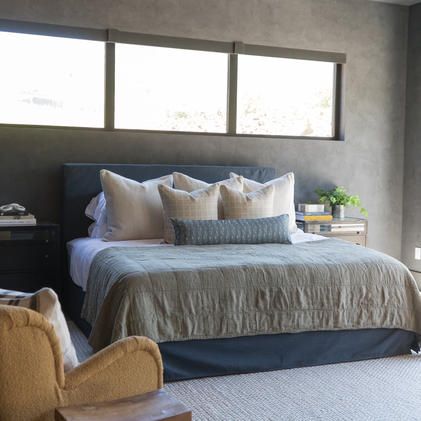 Taupe-colored window treatment with square panels installed above a bedroom bed.