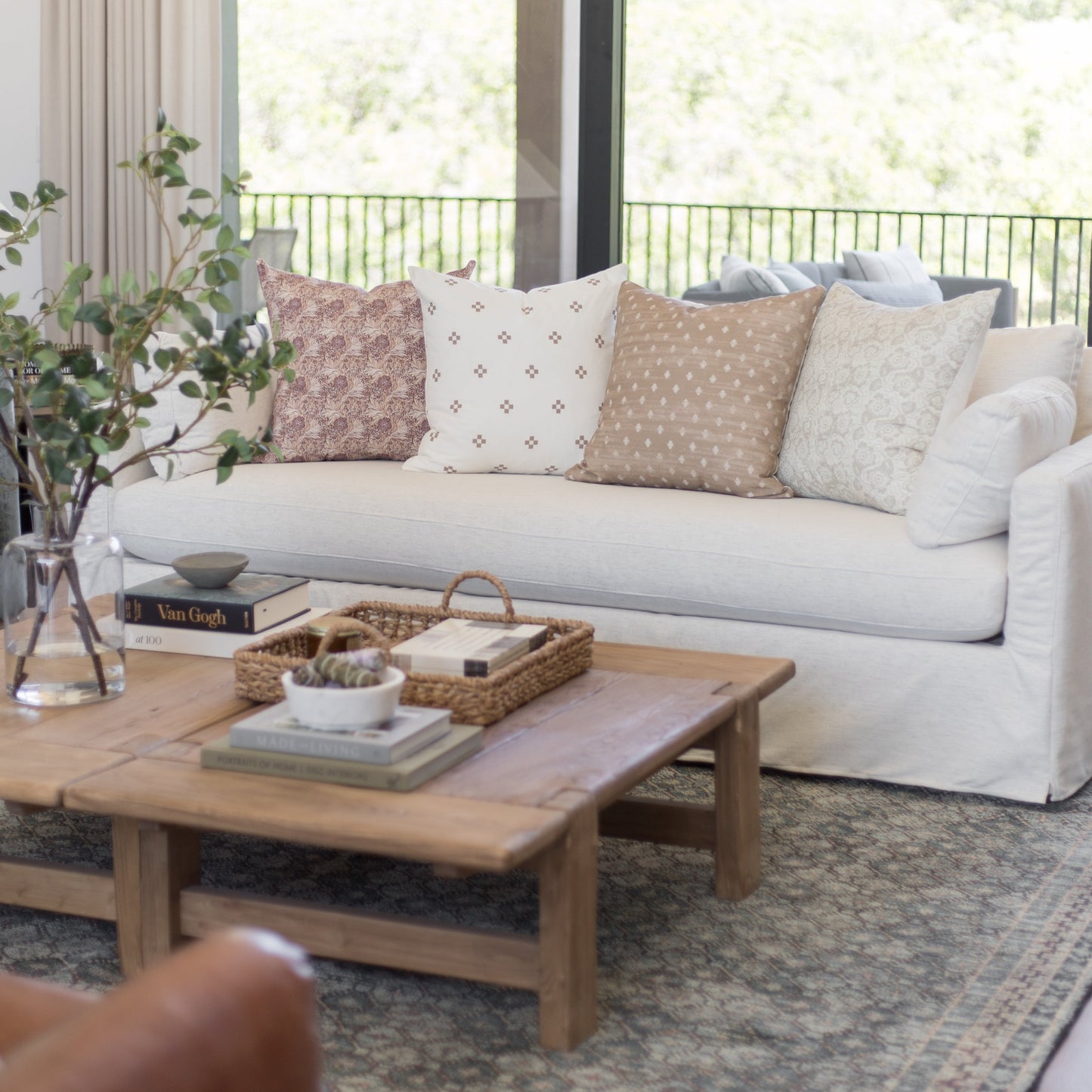 Four decorative pillows in varying patterns including floral, geometric, and solid designs arranged on a light gray sofa.