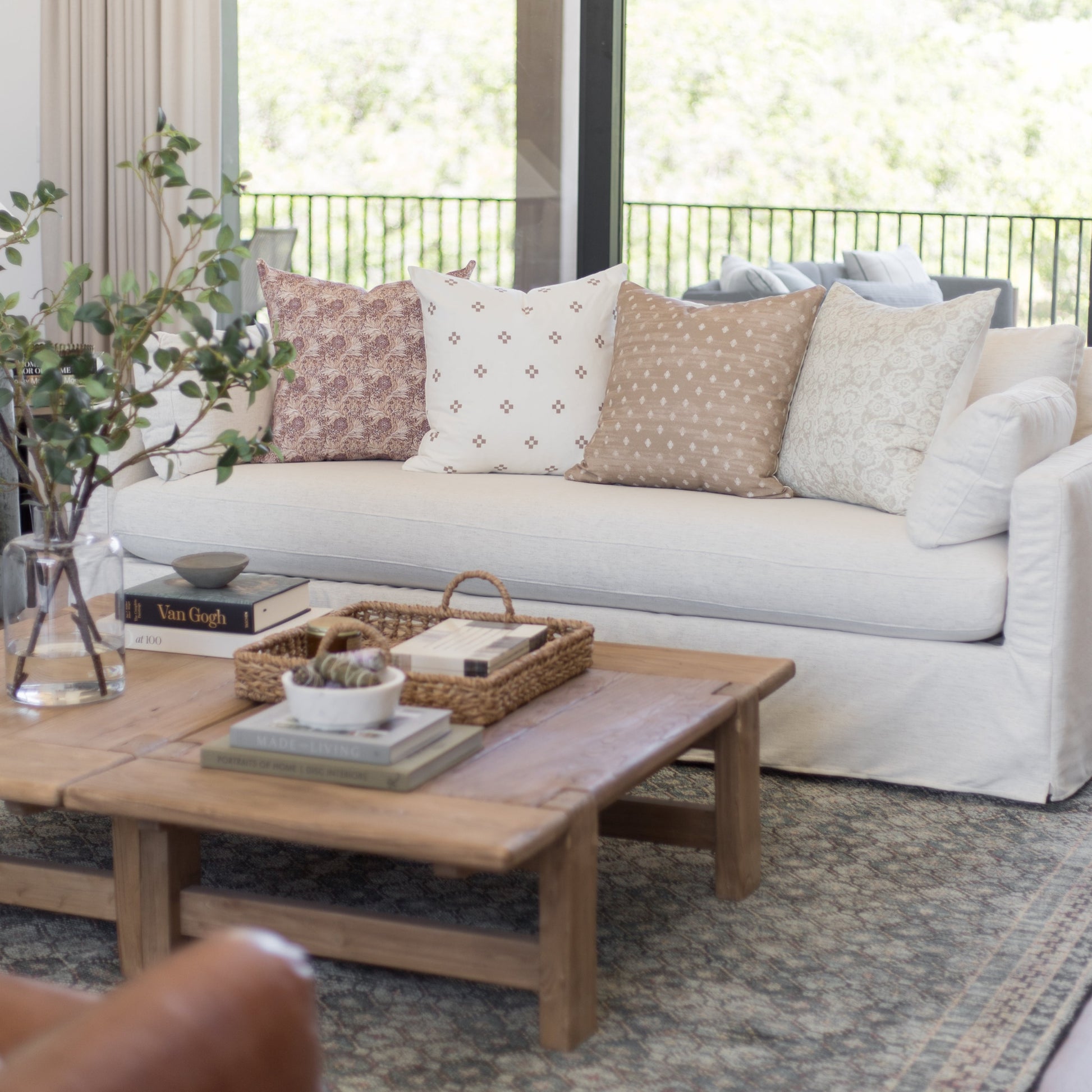 Four decorative pillows in varying patterns including floral, geometric, and solid designs arranged on a light gray sofa.