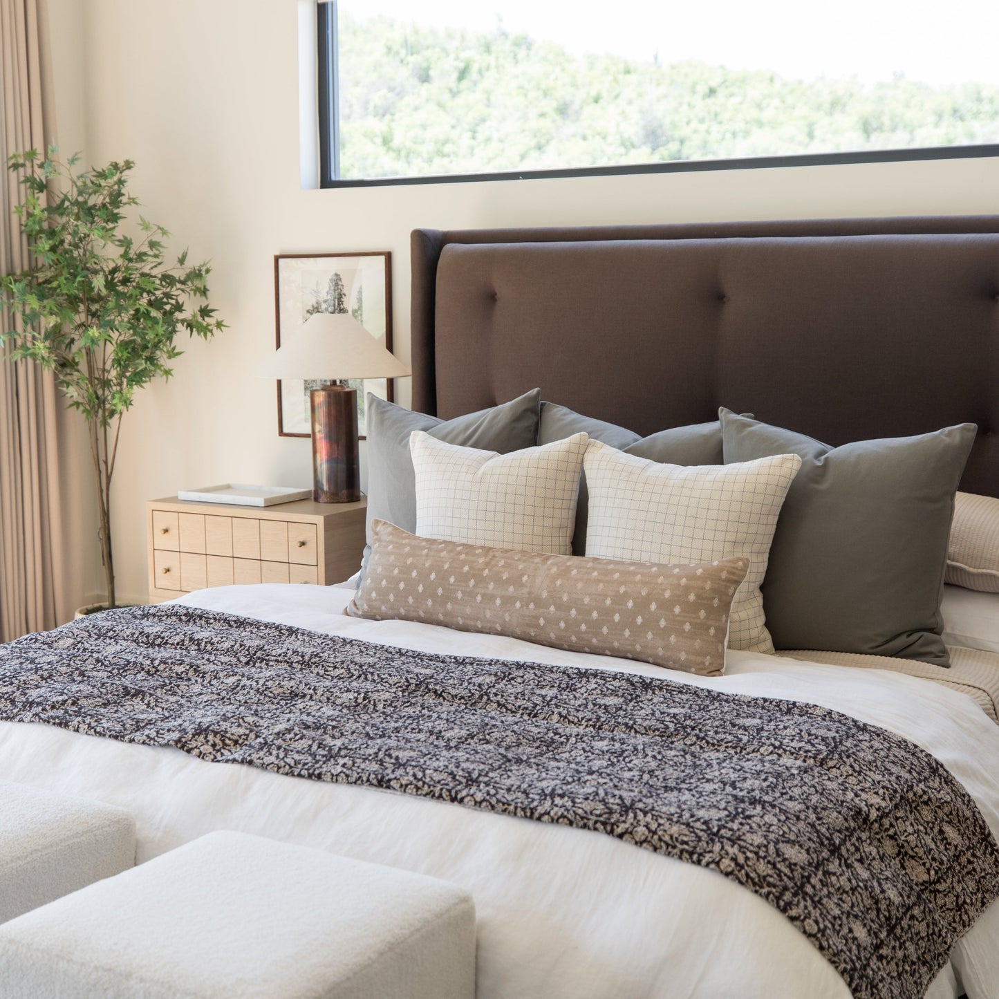 Gray and charcoal grid-patterned lumbar pillow displayed on a bed with coordinating pillows and bedding.