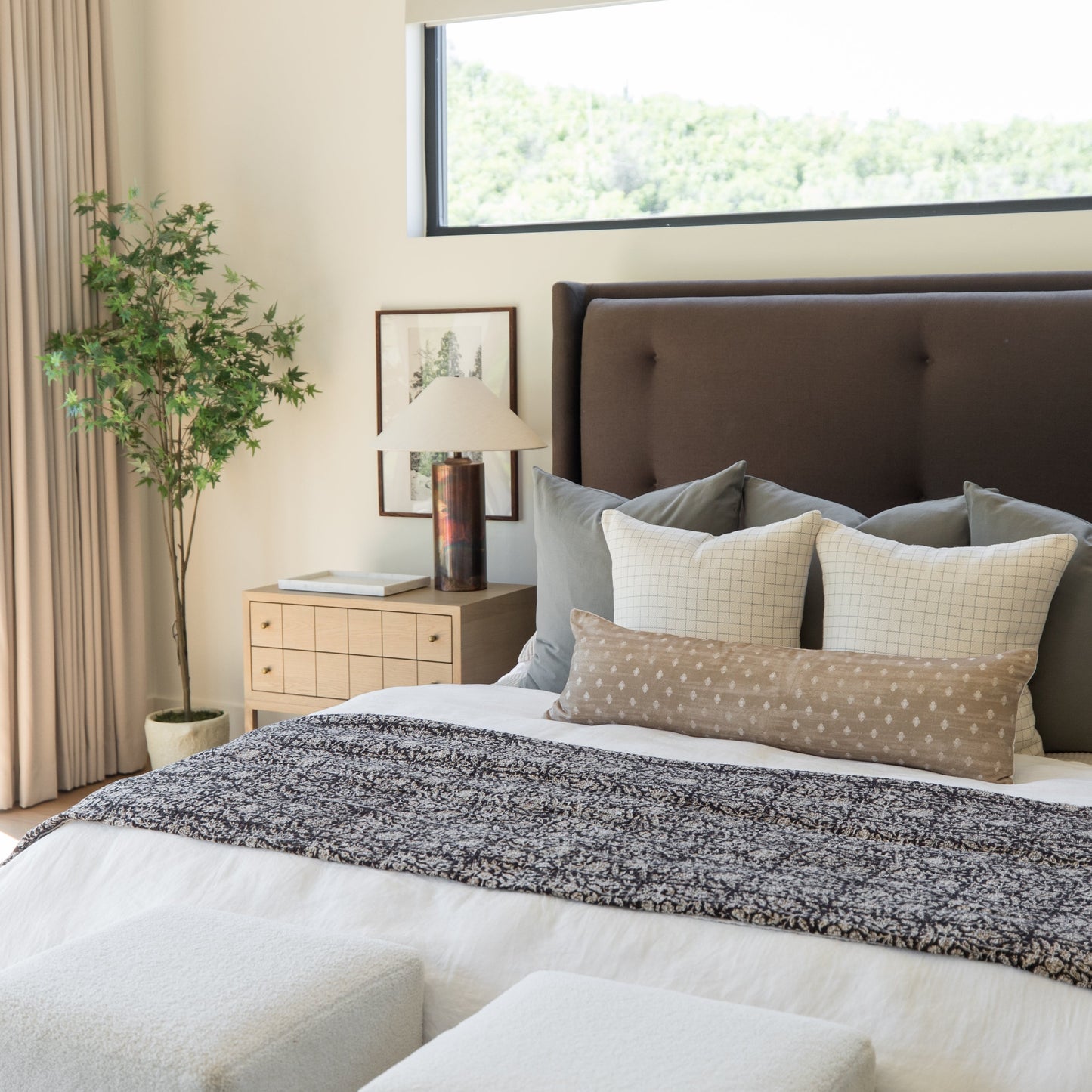 Dark speckled throw blanket draped across a bed with patterned pillows in a modern bedroom setting.