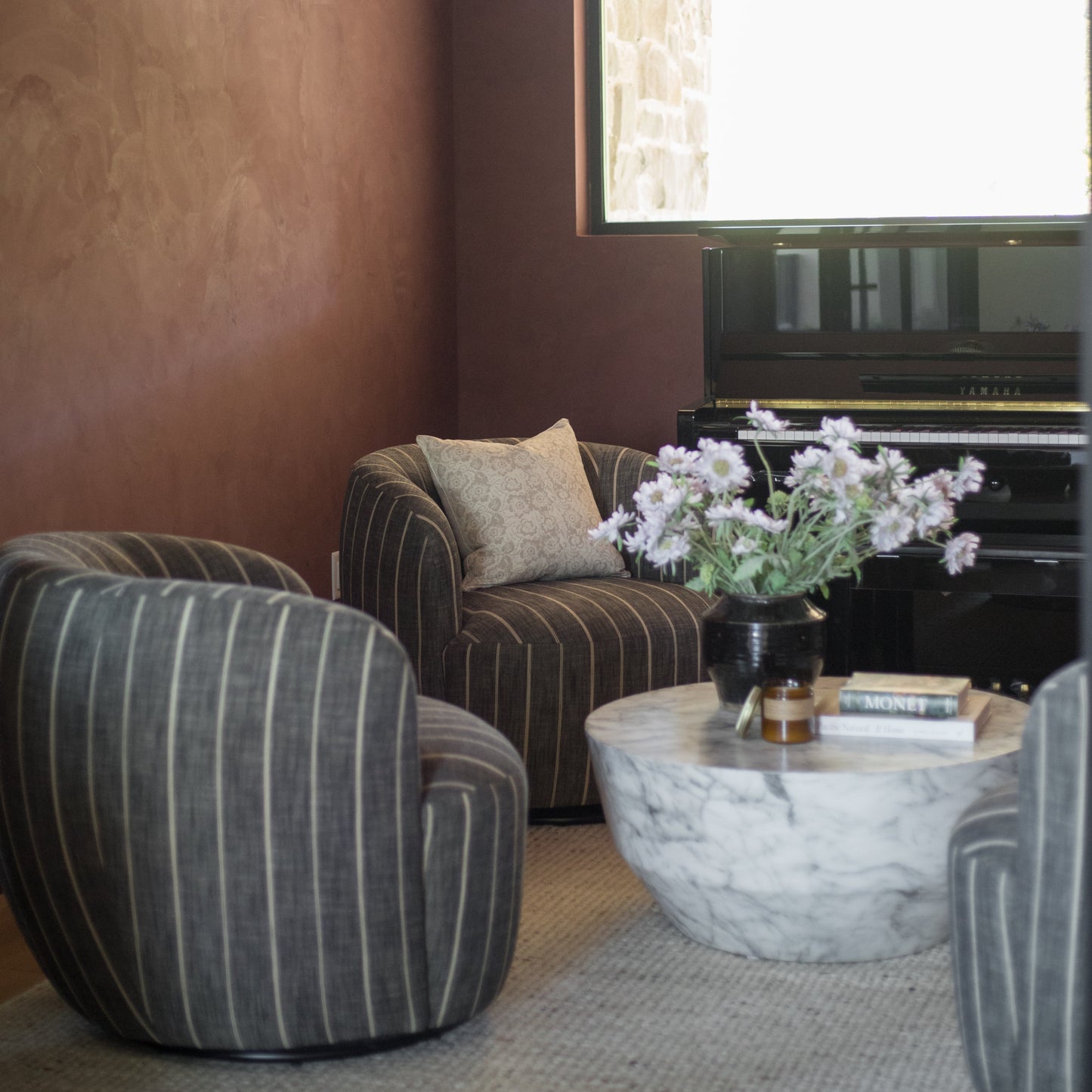 Beige linen pillow cover with subtle floral pattern, displayed on striped chair in modern living room setting.