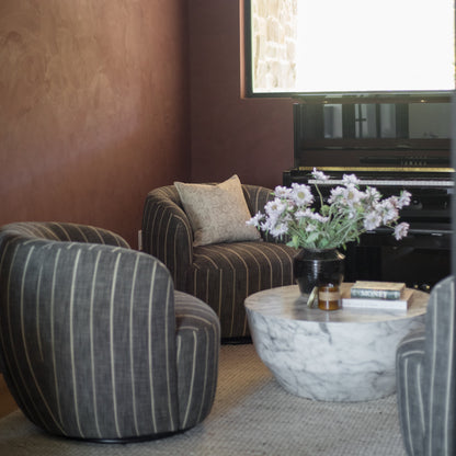 Beige linen pillow cover with subtle floral pattern, displayed on striped chair in modern living room setting.