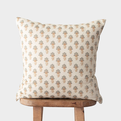Cream pillow with repeating tan and gray floral motifs displayed on wooden chair.