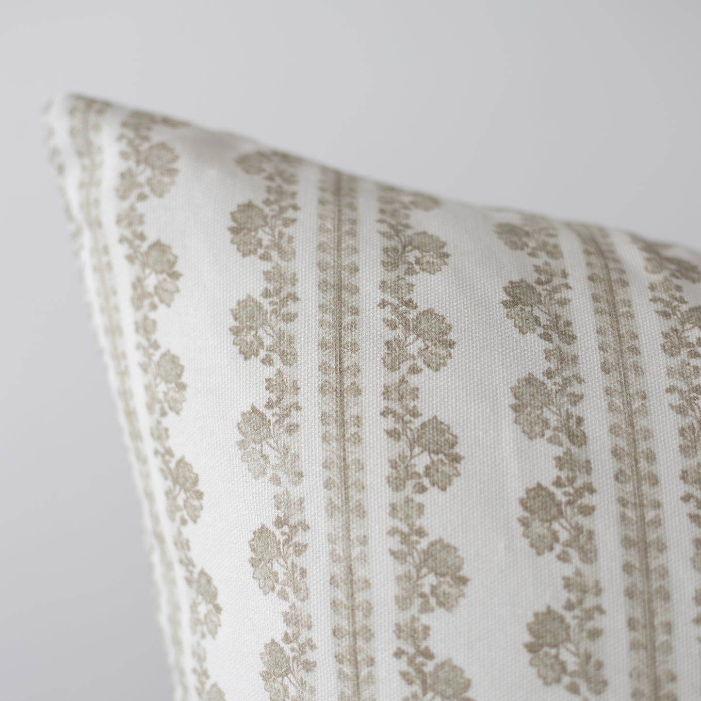 Cream linen pillow with tan damask pattern and vertical stripes, angled corner view.