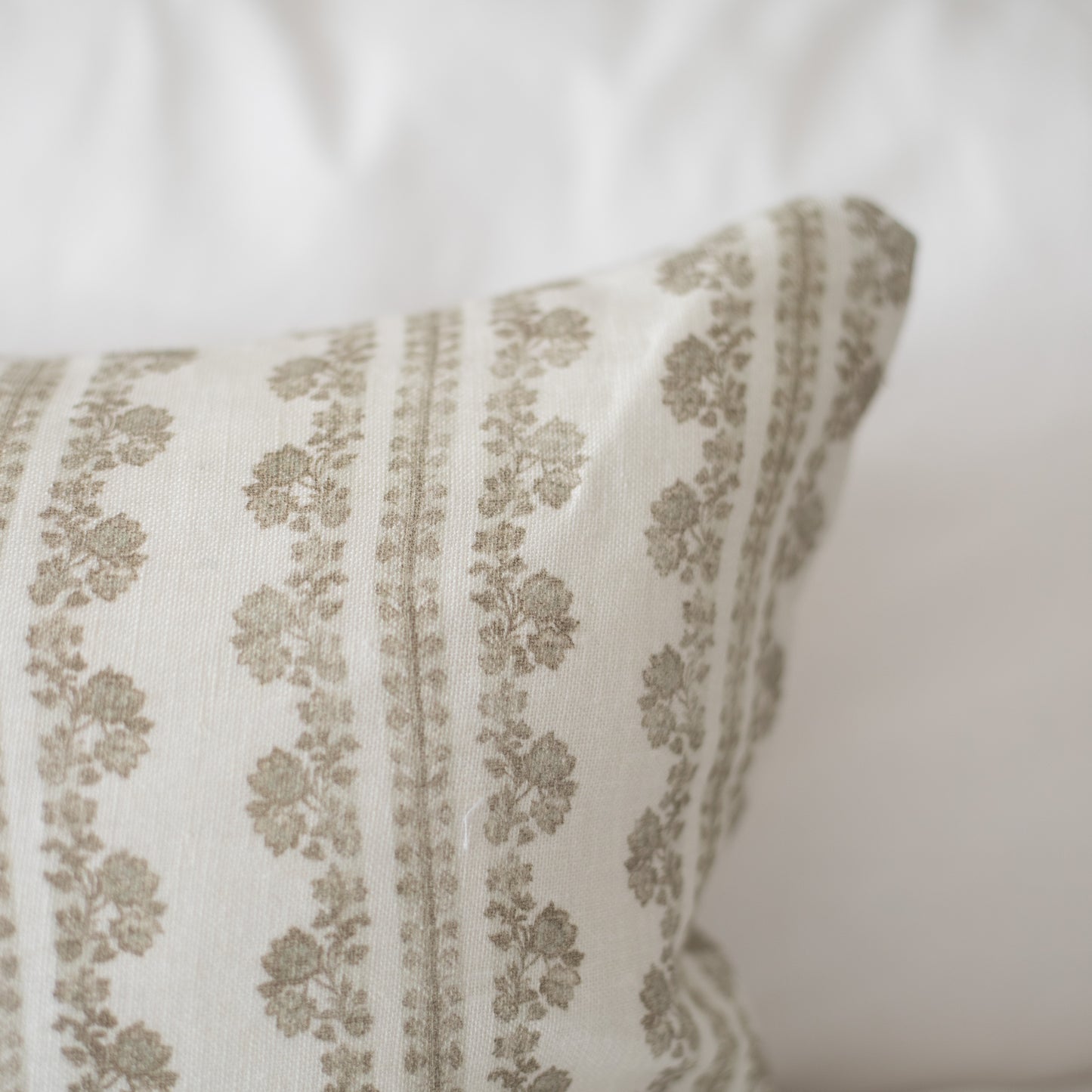 Cream linen pillow with vertical stripes of tan floral motifs and matching edge trim.