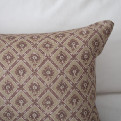 Rectangular pillow with cream and mauve geometric diamond pattern containing small floral motifs.