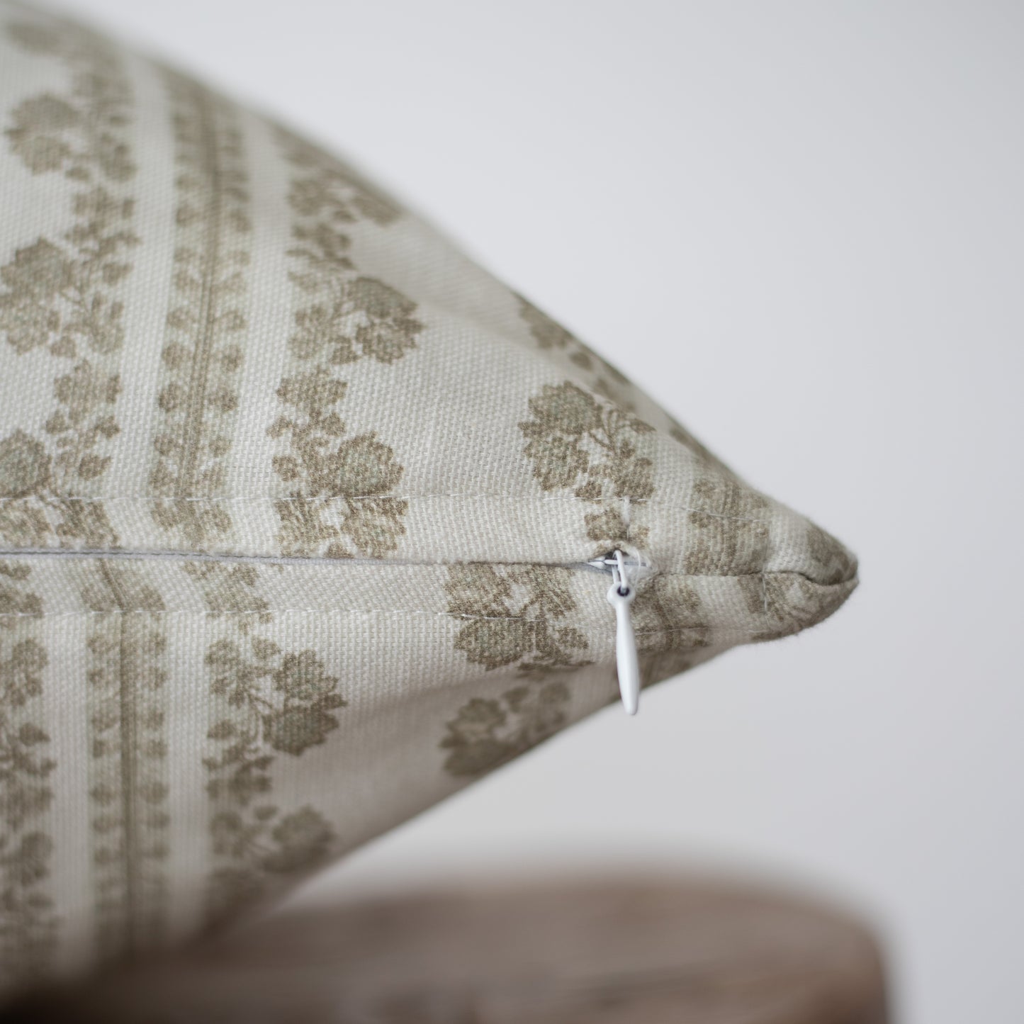 Cream linen pillow with taupe damask pattern and white zipper closure.