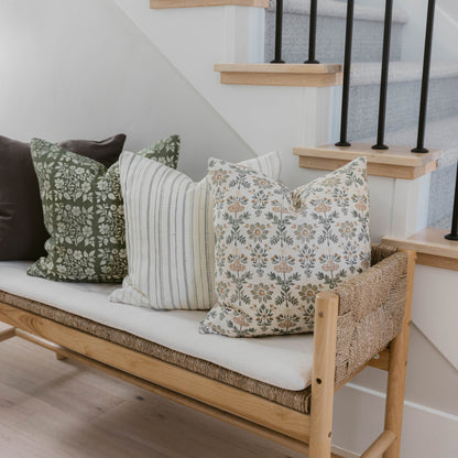 Four decorative pillows with varied patterns including floral, striped, and botanical designs in green, cream, and neutral to