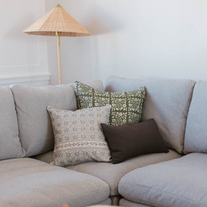 Beige lumbar pillow with geometric pattern displayed on gray sofa with coordinating decorative pillows.