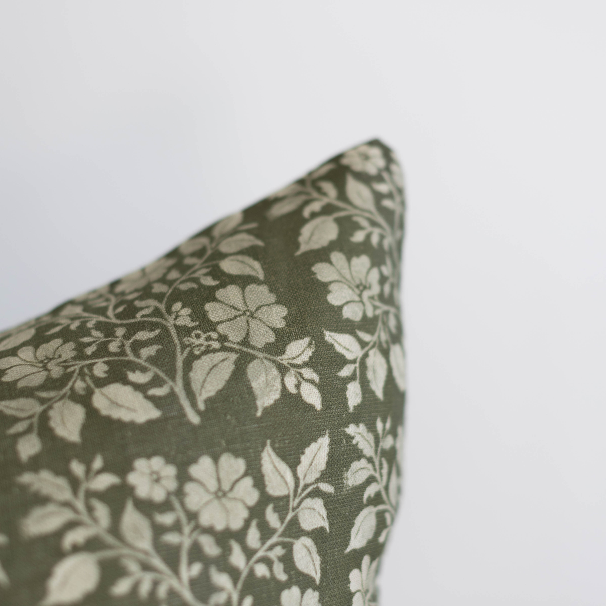 Sage green linen pillow with cream floral and botanical leaf pattern.
