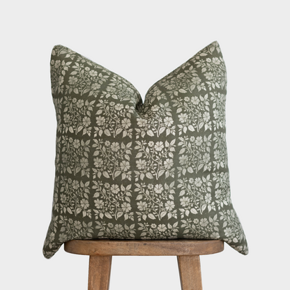Sage green linen pillow cover with cream floral and leaf pattern, displayed on wooden stand.