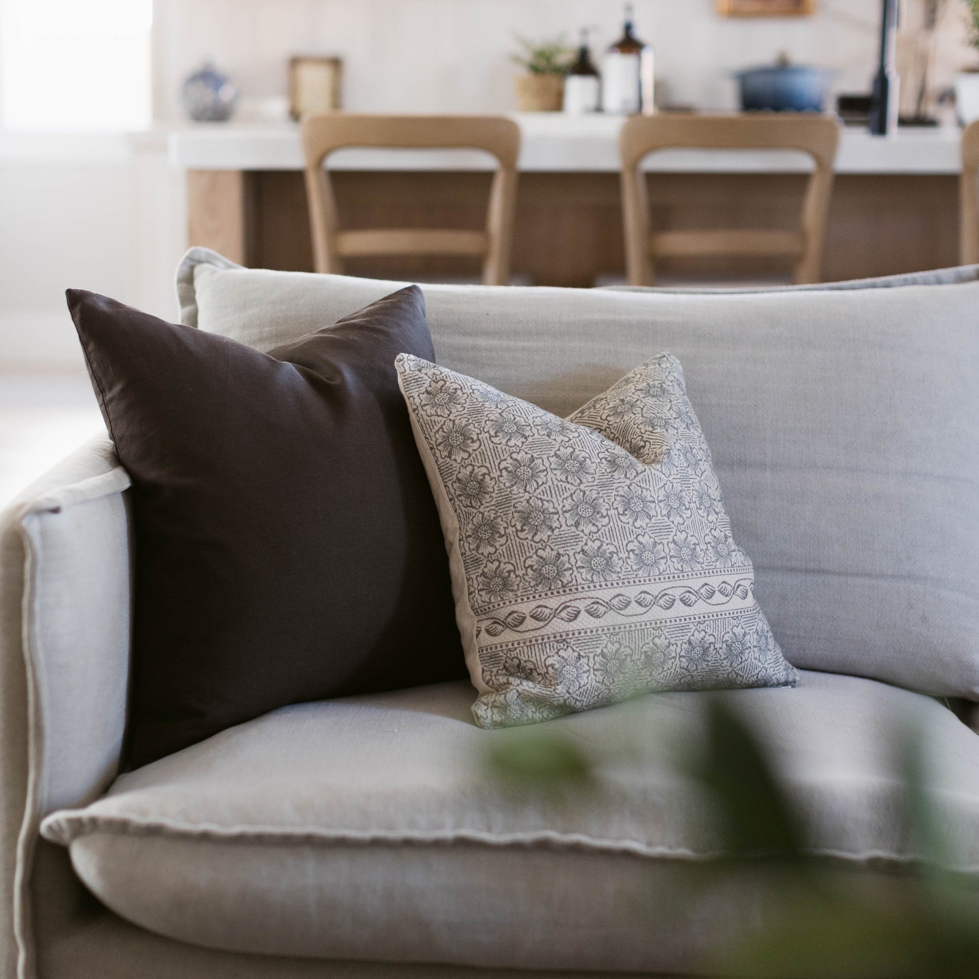 Gray sofa with black and patterned double-sided throw pillows in a living room setting.