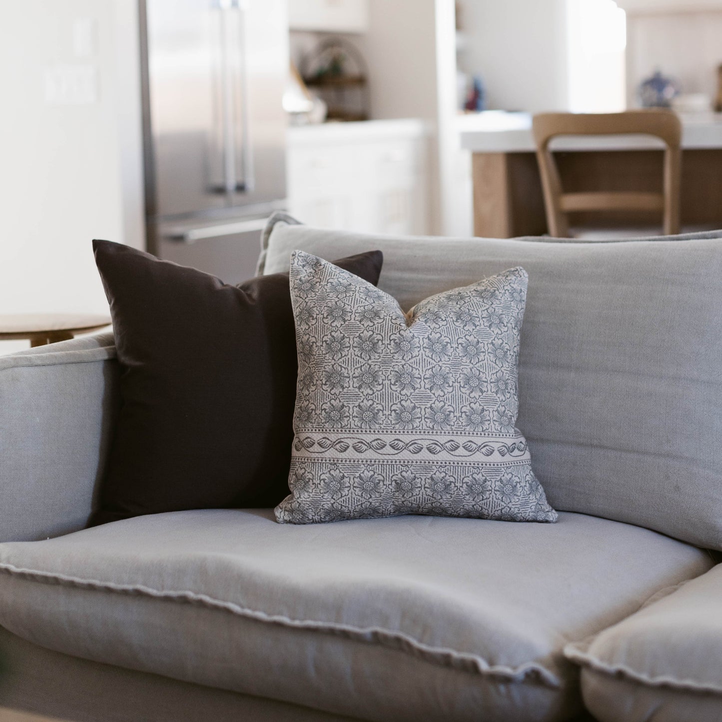 Two decorative pillows on a gray sofa: one black solid pillow and one gray patterned pillow with geometric designs.