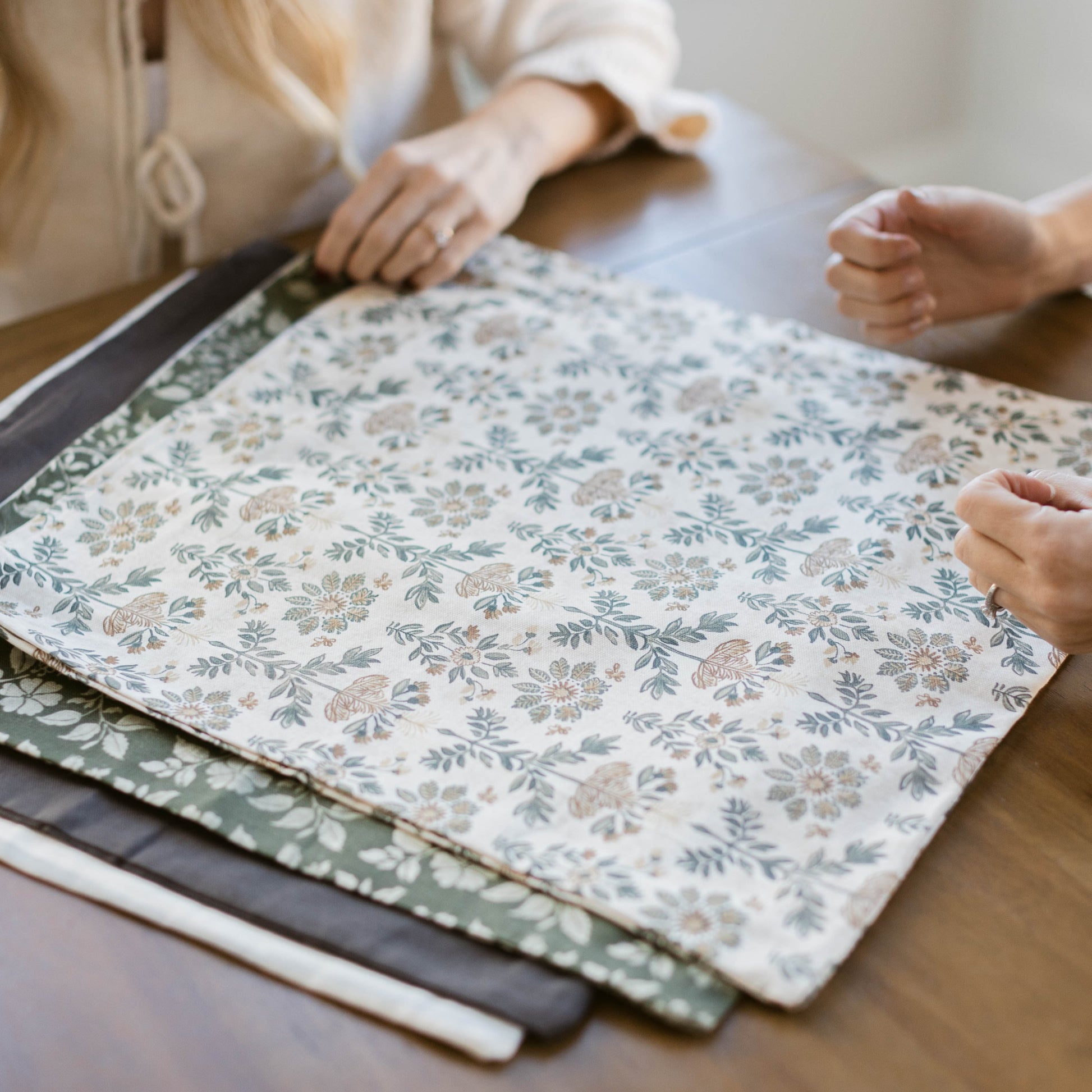 Four fabric swatches in varying sizes displaying floral and botanical prints in blue, gray, and neutral tones.