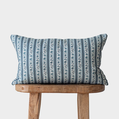 Blue and white striped pillow with floral motif pattern displayed on wooden chair.
