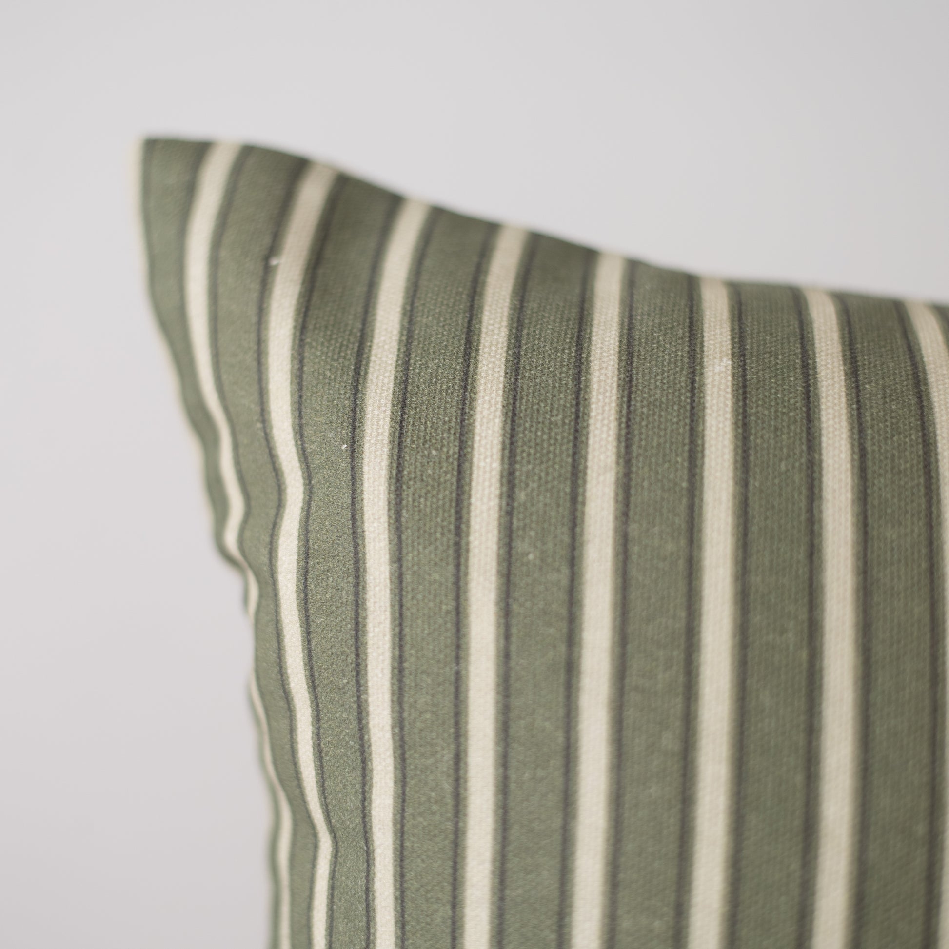 Sage green and cream striped cushion cover with vertical woven stripes and piped edge detail.