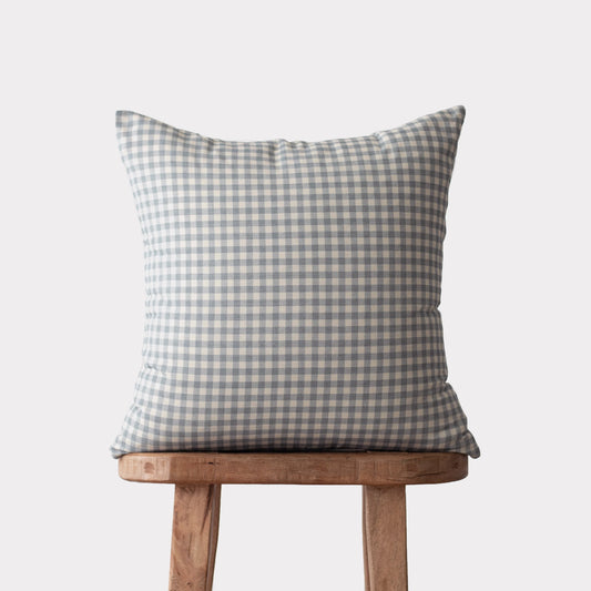 Dusty blue and white gingham checkered pillow on wooden stool.