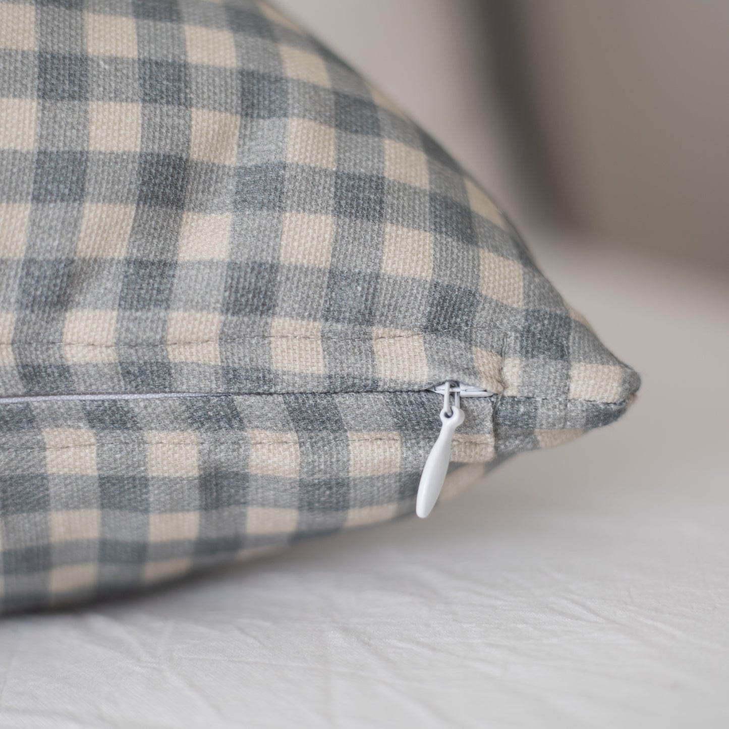Dusty blue and cream gingham pillow with white zipper closure, angled view.