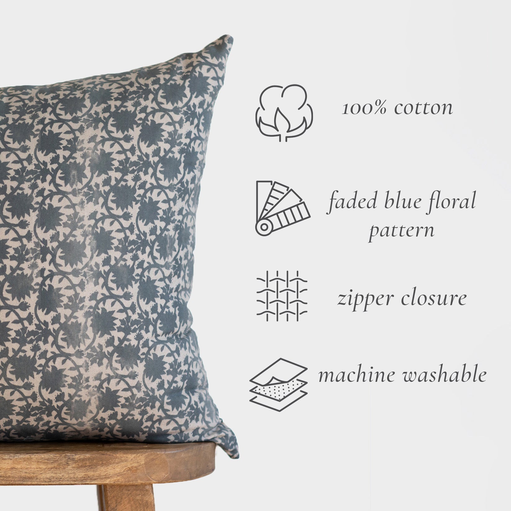 Rectangular throw pillow with faded blue and cream damask floral pattern, displayed on wooden stand.