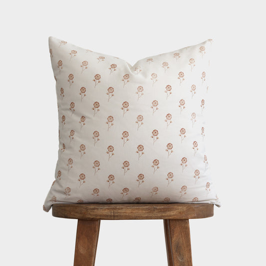 Cream pillow with small buttercup flower pattern in tan, displayed on wooden stool.