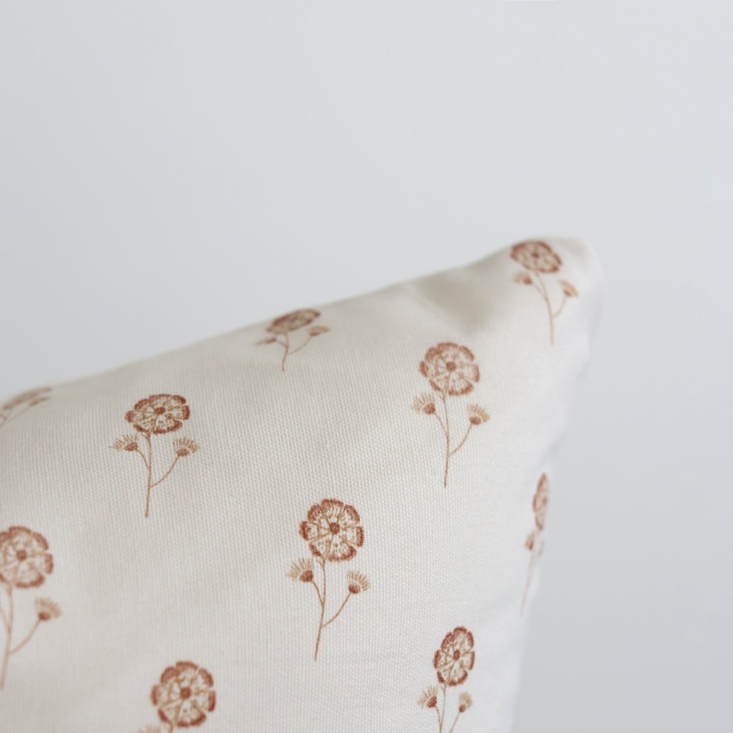 Cream pillow with scattered tan dandelion flower print.
