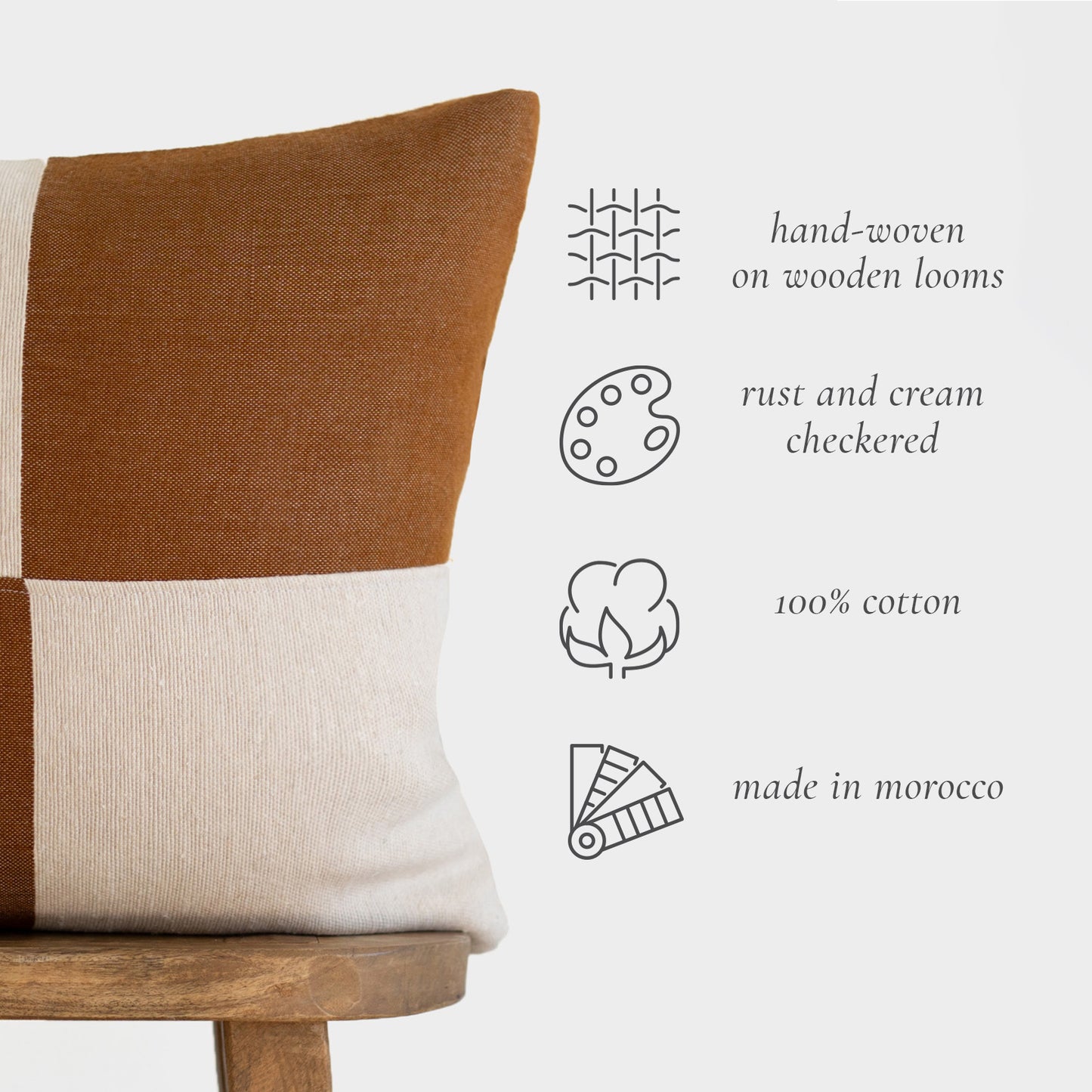 Rust and cream checkered 22-inch pillow with 100% cotton construction and color-blocked design on wooden chair.